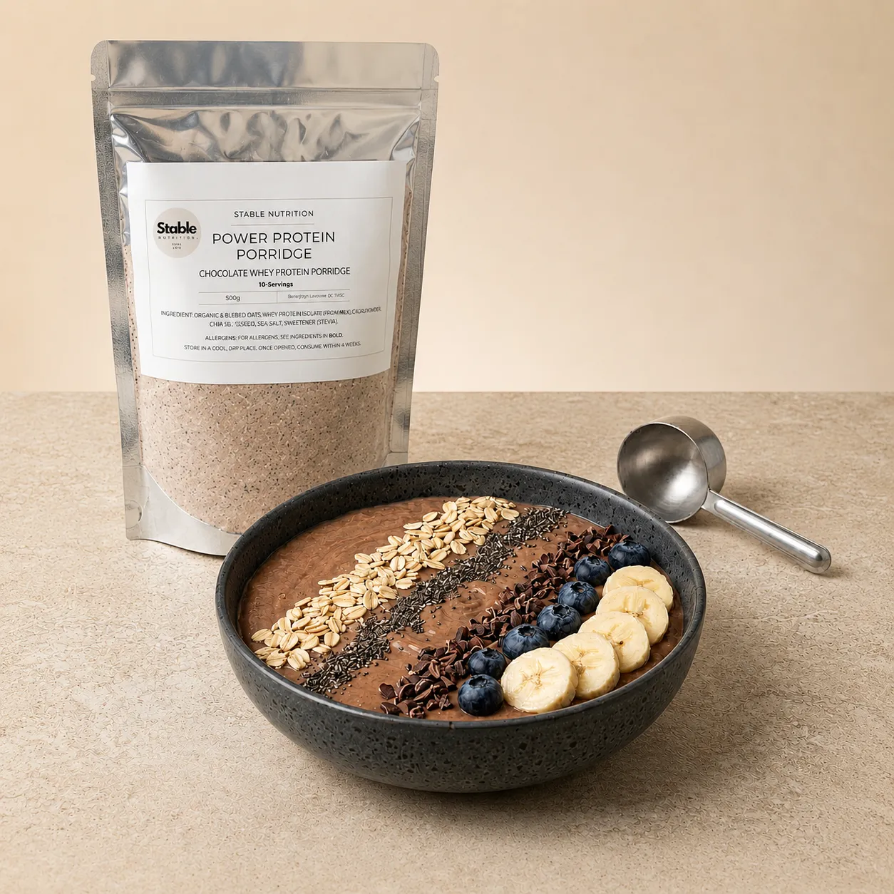 Stable Nutrition Power Protein Porridge pouch beside a chocolate porridge bowl topped with oats, chia, blueberries and banana.